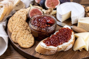 Fig jam served on a cheese board with crackers and soft cheese