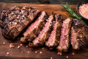 Grilled steak finished with coarse Himalayan pink salt crystals on a cutting board