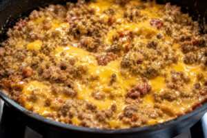 Ground beef, sausage, and melted Velveeta cheese mixture for Hanky Panky recipe in a skillet