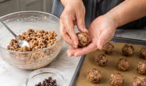 Hands rolling protein ball mixture into bite-sized balls on a kitchen counter
